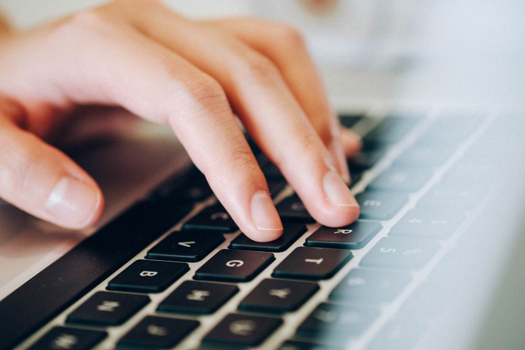 prsti koji kucaju na tastaturi laptopa